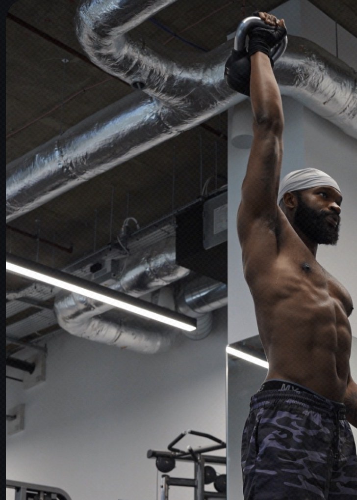 Haqq holding a kettlebell overhead in the gym